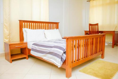ein Schlafzimmer mit einem Bett mit einem Holzrahmen und einem Nachttisch in der Unterkunft Ambiere House in Mtwara