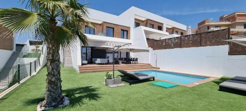 a house with a palm tree and a swimming pool at VILLA VERAMAR in Finestrat