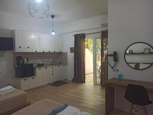 uma cozinha com armários brancos, uma mesa e um espelho em Bourbos Summer Rooms em Himare