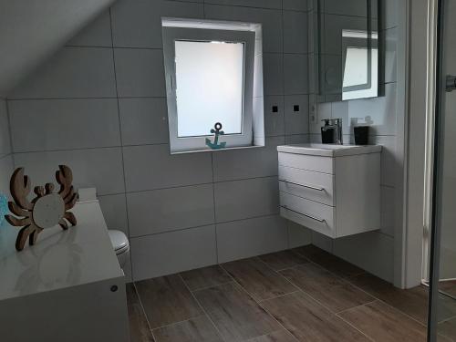 baño con aseo y lavabo y ventana en Ferienwohnung Muh - Ostfriesland nähe Nordsee, en Rechtsupweg