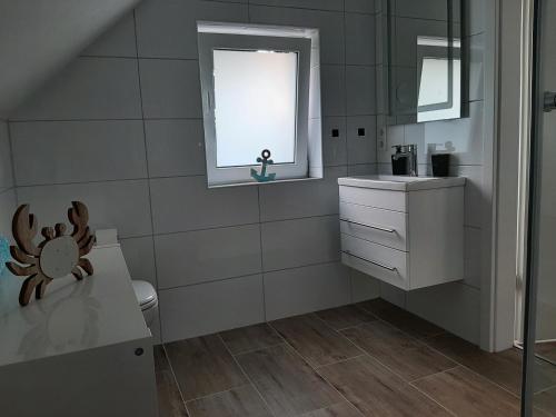 Un baño con inodoro, lavabo y ventana. en Ferienwohnung Muh - Ostfriesland nähe Nordsee, en Rechtsupweg