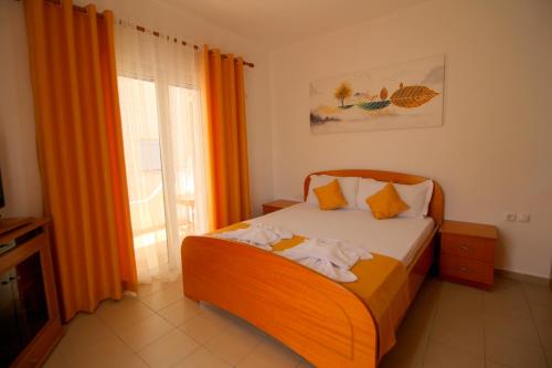 a small bedroom with a bed with orange curtains at Hotel Vila Kapllani in Sarandë