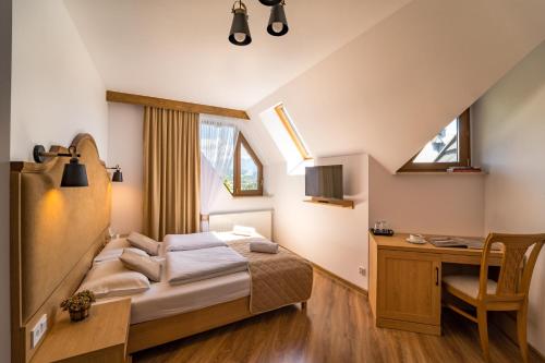 a bedroom with a bed and a desk and window at Miodowy Dworek in Bukowina Tatrzańska
