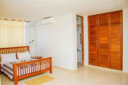 a bedroom with a bed and a wooden door at Ambiere House in Mtwara