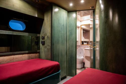 a small room with a red bed and a toilet at Yacht San Lorenzo 22 in La Spezia