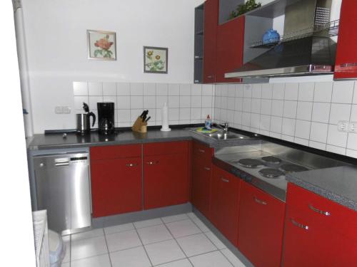 een keuken met rode kasten en een wastafel bij 54 Appartement Residenz Bellevue U in Zinnowitz