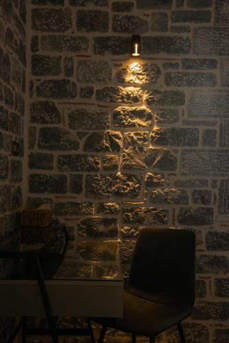 a chair in front of a stone wall with a light at Manifest Boutique Hotel in Oítilon
