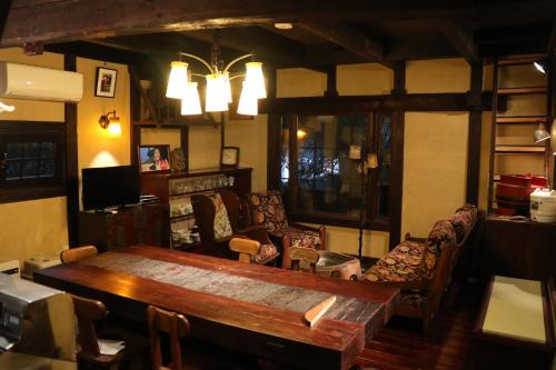 uma sala de estar com uma mesa de madeira e cadeiras em Guest House Dohei em Kamakura