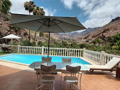 a table with an umbrella next to a swimming pool at Time To Experience in Salobre