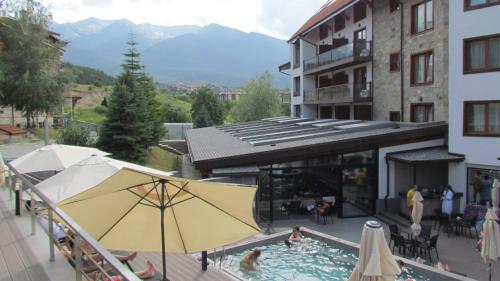 a swimming pool with a yellow umbrella next to a building at St Ivan Rilski Spa Luxury apartment Bansko & Free SPA in Bansko