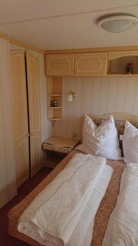 HohenferchesarMobilheim Monika的房间里有一张铺着白色床单和枕头的床