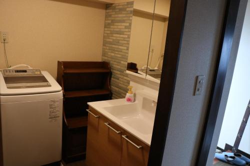 a small bathroom with a sink and a stove at Guest House Dohei in Kamakura
