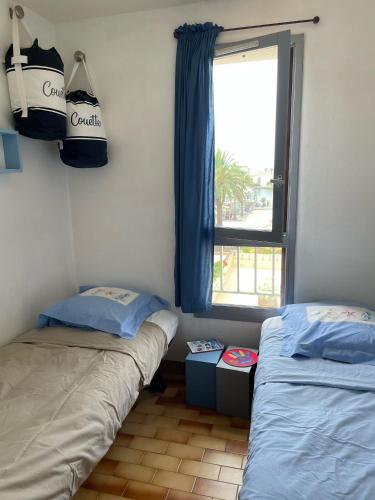 une chambre avec deux lits jumeaux et une fenêtre dans l'établissement Cap d’Agde Centre port avec parking privé et belle vue port et mer, au Cap d'Agde