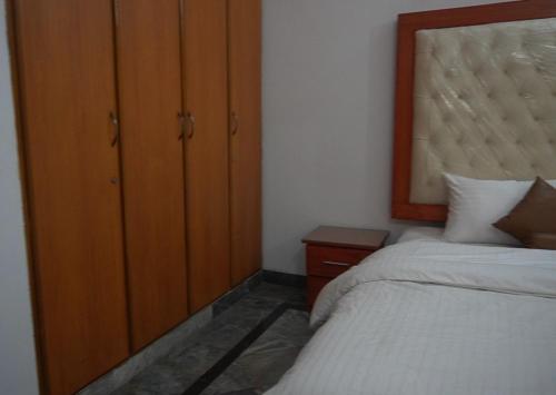 a bedroom with two beds and a wooden cabinet at Family Guest House Lahore Near Airport in Lahore