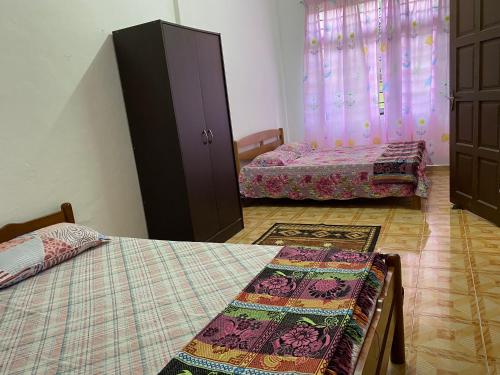a bedroom with two beds and a dresser and curtains at Homestay Taman Maktab Pengkalan Chepa in Pengkalan Cepa
