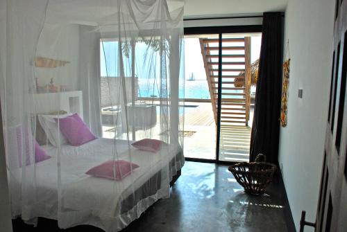 ein Schlafzimmer mit einem Bett mit rosa Kissen und einem Balkon in der Unterkunft OCEANFRONT VILLA WITH ACCES CARIBBEAN SEA in Kralendijk