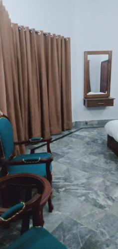 a room with chairs and a bed and a mirror at Family Guest House Lahore Near Airport in Lahore