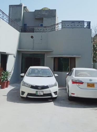 two white cars parked in front of a building at Family Guest House Lahore Near Airport in Lahore