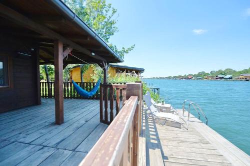 a wooden dock with a hammock on the water at Filipa River House Ada Bojana in Ulcinj