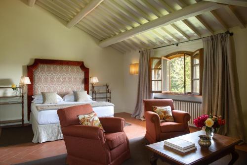a bedroom with a bed and two chairs and a table at Viesca Toscana Suites & Villas in Reggello
