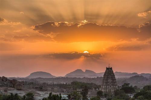 a sunset over a city with a building in the foreground at Vicky's Home Stay Hampi in Hampi