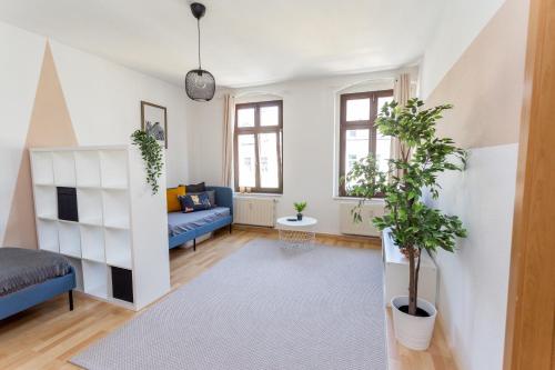 a living room with a blue couch and plants in it at FULL HOUSE Studios - Apartment Namibia in Chemnitz