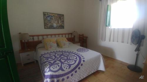 Can Xumeu Miquel في سانت فيران دي سيس روكيه: غرفة نوم مع سرير وبطانية بيضاء وأرجوانية