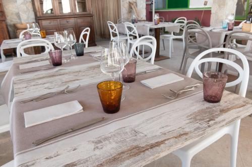 a wooden table with wine glasses on top of it at Hotel Villa A Mare in Rodi Garganico