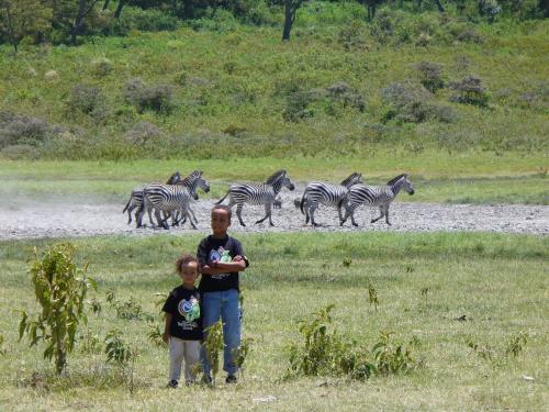 two boys standing in a field with a herd of zebras at Meru Mbega Lodge in Usa River