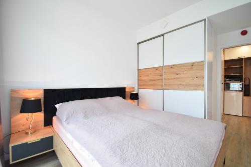 a bedroom with a large white bed and a kitchen at Apartament Rogowo 117L in Rogowo