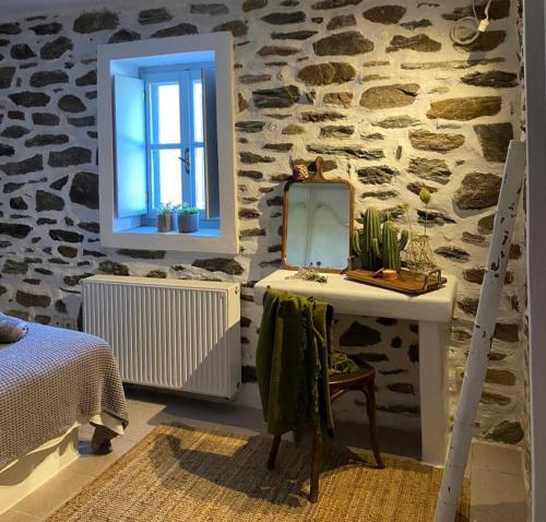 a bedroom with a stone wall with a mirror and a table at Beyond the tree in Kionia