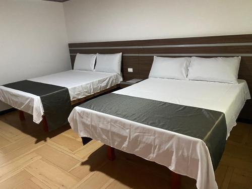two beds in a small room withermottermott at Hotel Suit Esmeralda in Girardot