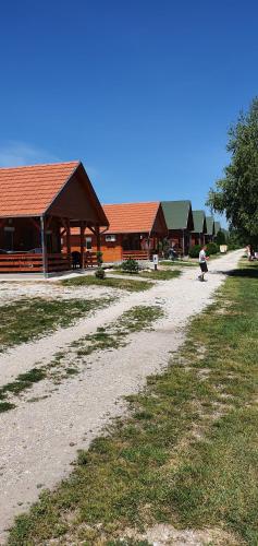 a person riding a skateboard down a dirt road next to a building at Sárberki Horgásztó in Lenti