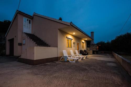 um grupo de cadeiras brancas sentadas fora de uma casa em Kuća za odmor Boris em Podstrana