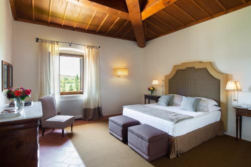 a bedroom with a bed and a desk and a window at Viesca Toscana Suites & Villas in Reggello