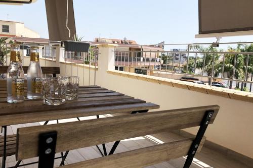 a wooden table with bottles and glasses on a balcony at Accòmodati - Camere e Appartamenti in Marina di Gioiosa Ionica