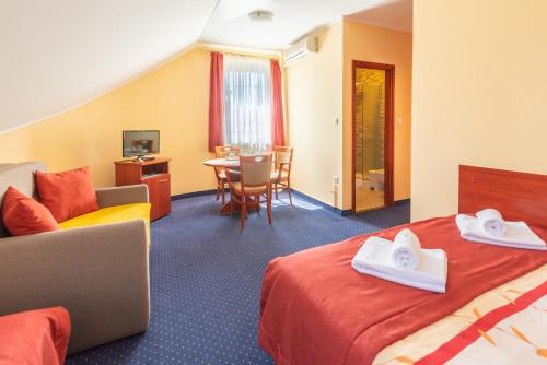 a hotel room with two beds and a table at Boglárka Panzió - Étterem in Mezőkövesd