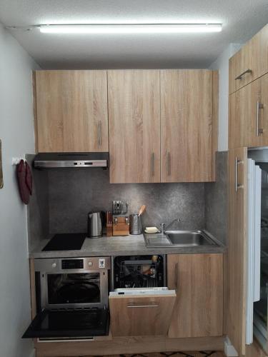una pequeña cocina con armarios de madera y fregadero en Valberg: au coeur de la station, en Péone