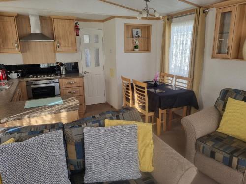 a kitchen and living room with a table and chairs at 8 BERTH DELUXE CARAVAN Pg156 GOLDEN PALM CHAPEL ST LEONARDS in Chapel Saint Leonards