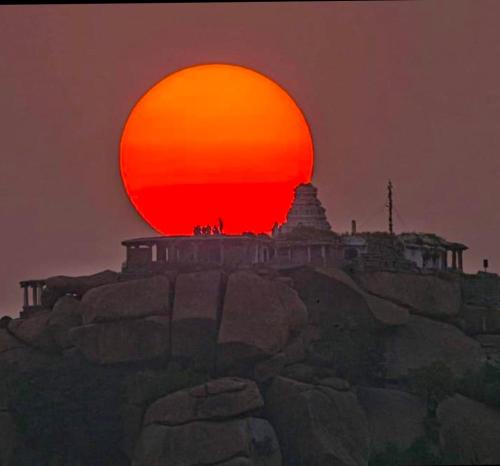 a sun setting on top of a mountain at Vicky's Home Stay Hampi in Hampi