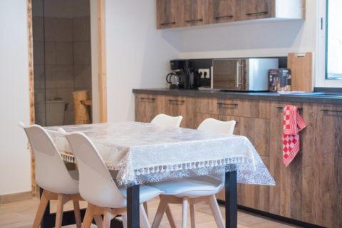 una cocina con una mesa con sillas blancas y una barra en Ranch du Haut-Languedoc en La Salvetat