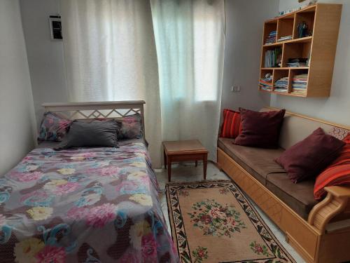 a small bedroom with a bed and a couch at jolie appart au centre urbain nord in Tunis