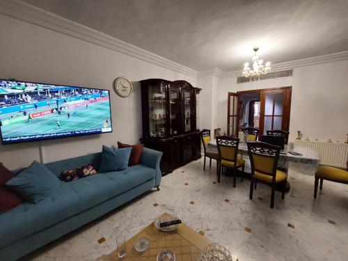 ein Wohnzimmer mit einem blauen Sofa und einem TV in der Unterkunft jolie appart au centre urbain nord in Tunis