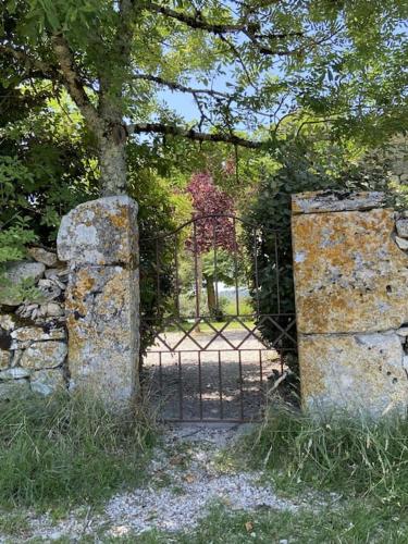 an iron gate with a tree and a stone wall at Cahors - Lot - Les Lumières du Causse - Domaine en pierres blanches avec vue sur les causses in Bellefont-La Rauze