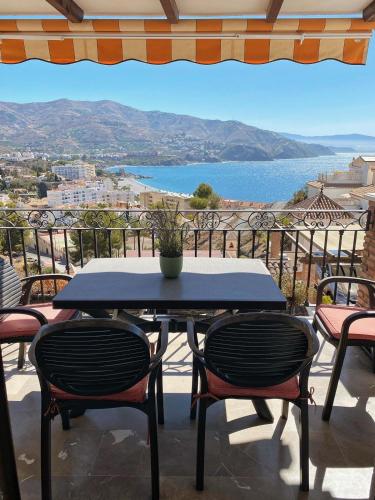 una mesa y sillas en un balcón con vistas al océano en Lambda LI, en Almuñécar