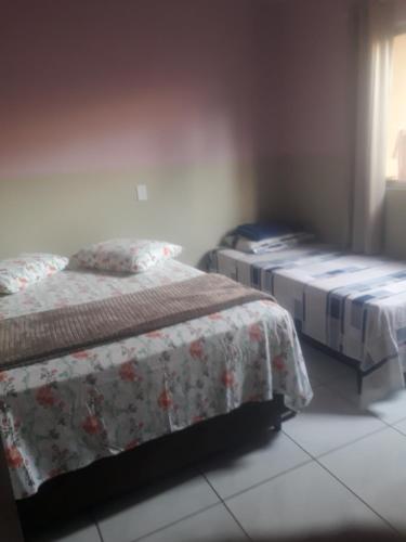 Un dormitorio con 2 camas y un banco. en Aluguel casa Bombinhas, en Bombinhas