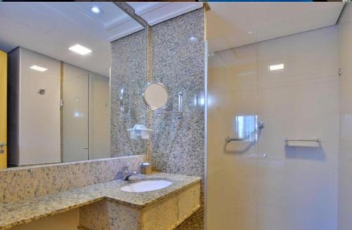 W łazience znajduje się umywalka, prysznic i lustro. w obiekcie FLAT DE ALTO PADRÃO - ENORME - CENTRO DA CIDADE - 2 Camas - 1 Queen e 1 Solteiro - Arrumação Diária Gratuita - Excelente Atendimento - VARANDA - COZINHA w mieście Brasília