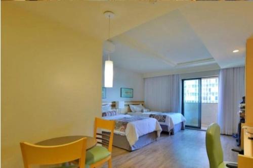 a hotel room with two beds and a table at FLAT DE ALTO PADRÃO - ENORME - CENTRO DA CIDADE - 2 Camas - 1 Queen e 1 Solteiro - Arrumação Diária Gratuita - Excelente Atendimento - VARANDA - COZINHA in Brasilia