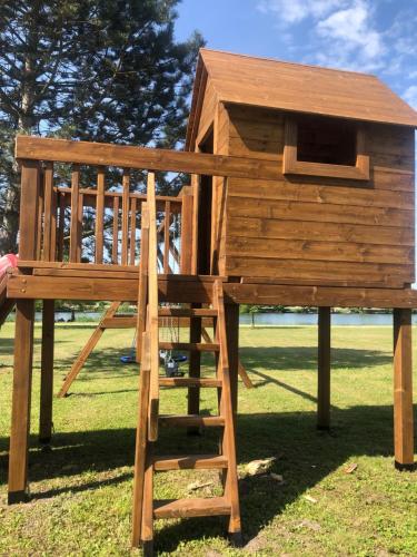 a wooden play structure with a ladder and a dog house at Sárberki Horgásztó in Lenti