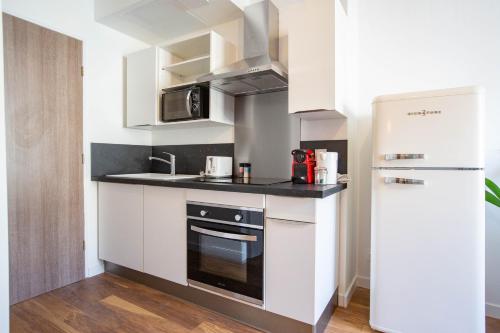 małą kuchnię z białymi szafkami i lodówką w obiekcie Faubourg des voyageurs n°6 w mieście Saran